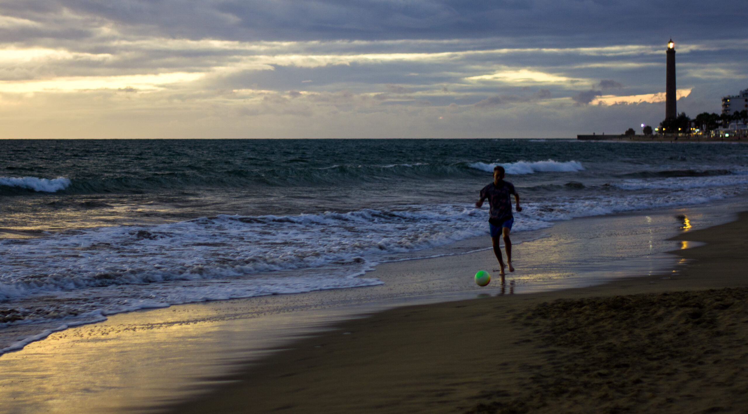 Het strand bij Maspalomas op Gran Canaria. Geschoten aan het einde van de dag met een voetballende jonge man langs de kust lijn.