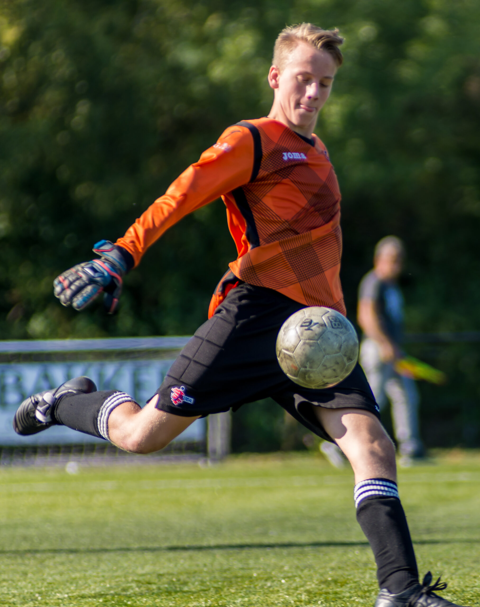 Doelman schiet een bal uit zijn hand.